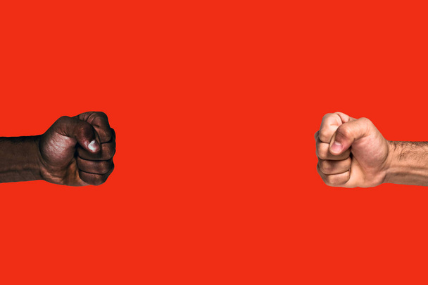 Multiculturele vuisten geheven. Afrikaanse zwarte vuist en Kaukasische witte vuist verhoogd oproep voor vrijheid en gelijkheid op een rode achtergrond. - Foto, afbeelding