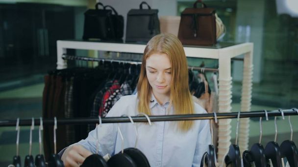 Atrakcyjne kobiety klient patrząc na ubrania na wieszaki w sklepie - Zdjęcie, obraz