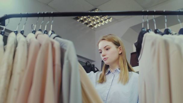 Женщина-клиент просматривает товары на стойке в магазине одежды
 - Фото, изображение