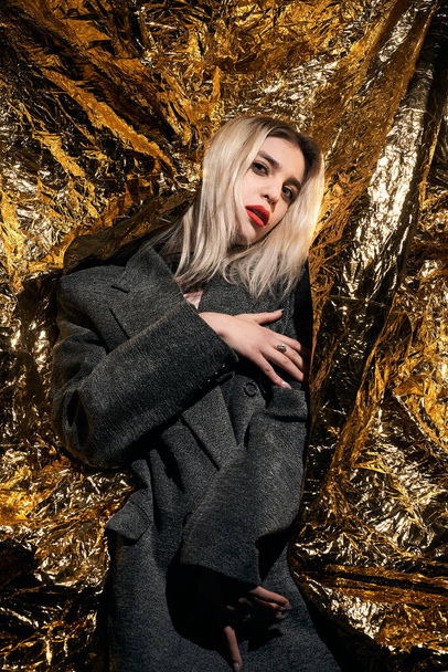 Fashionable girl posing in a jacket on a gold background. - Photo, Image