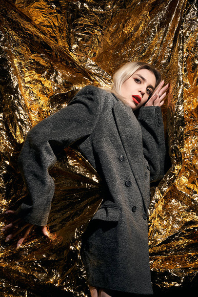 Fashionable girl posing in a jacket on a gold background. - Foto, afbeelding
