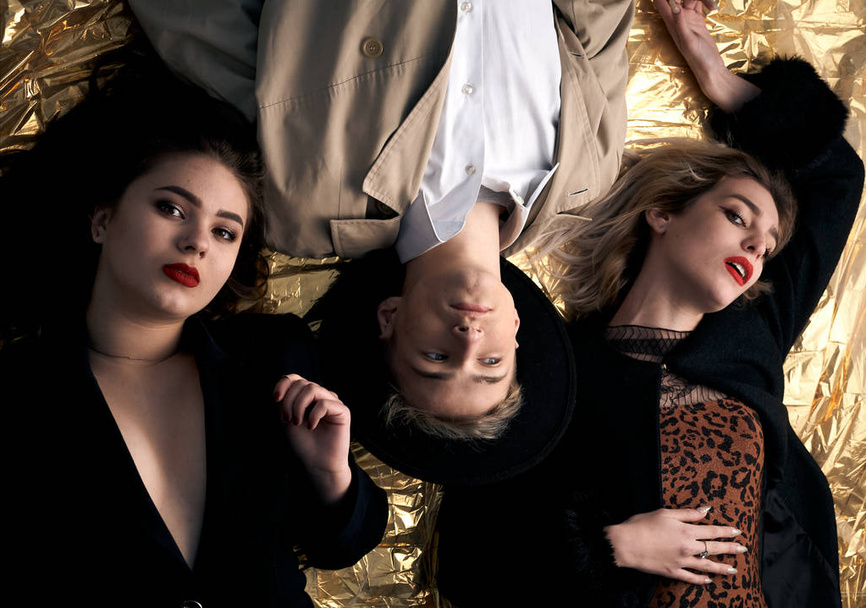 Stylish young people posing while lying on a gold background. - Photo, Image