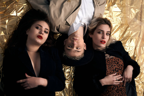 Jeunes gens élégants posant tout en étant couché sur un fond d'or. - Photo, image