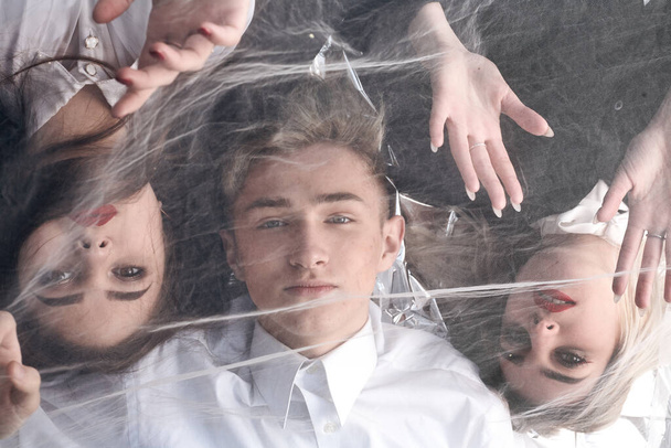 Portrait of three beautiful young people under a tulle fabric. - Photo, Image