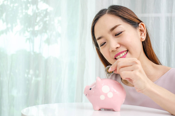 szczęśliwy Azji kobieta wprowadzenie pieniądze moneta w dla świnka dla oszczędność pieniądze bogactwo i finansowe pojęcie. - Zdjęcie, obraz