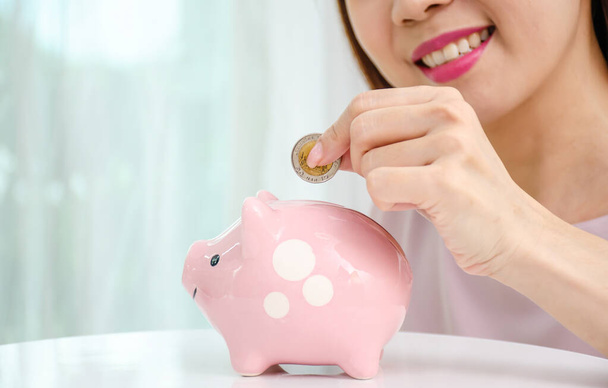 Šťastná asijská žena uvedení peněz mince do prasátko pro úsporu peněz bohatství a finanční koncept. - Fotografie, Obrázek