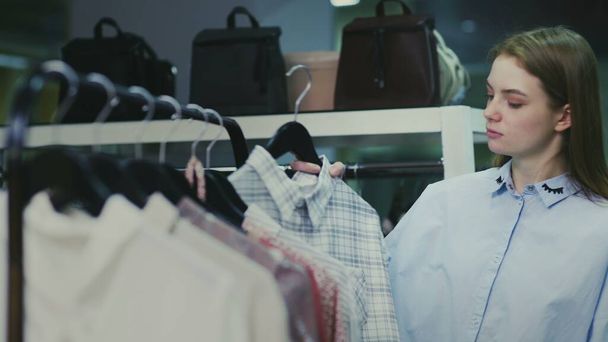 Mujer toma vestido de percha en la tienda boutique de ropa de moda
 - Foto, Imagen