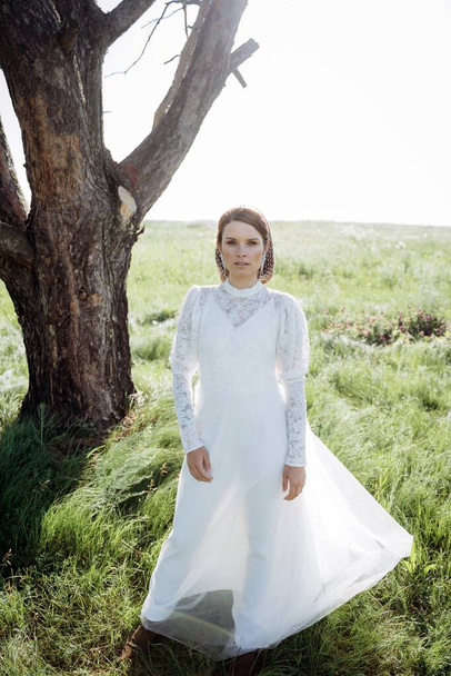fashionable woman in white dress standing under the tree in meadow - Fotoğraf, Görsel