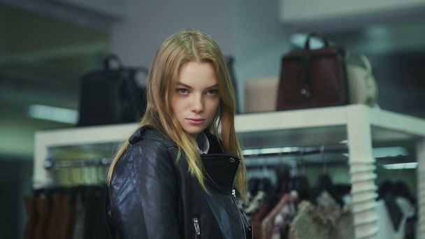 Young beautiful girl trying on a leather jacket in the store. - Photo, Image