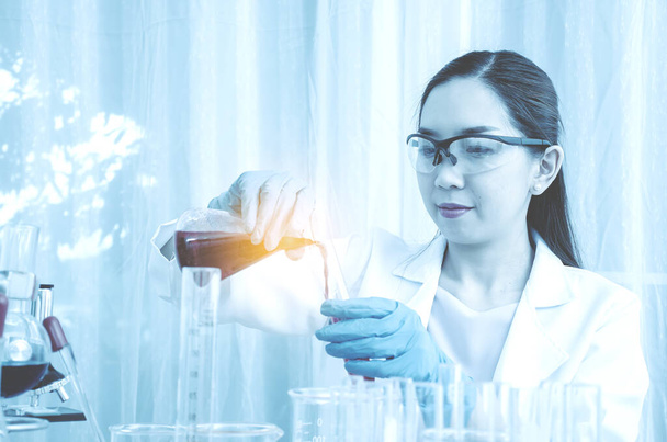 Вчений красива жінка досліджує і скидає медичні хімічні речовини зразок в пробірці в лабораторії, науці, хімії, технології, концепції біології
 - Фото, зображення
