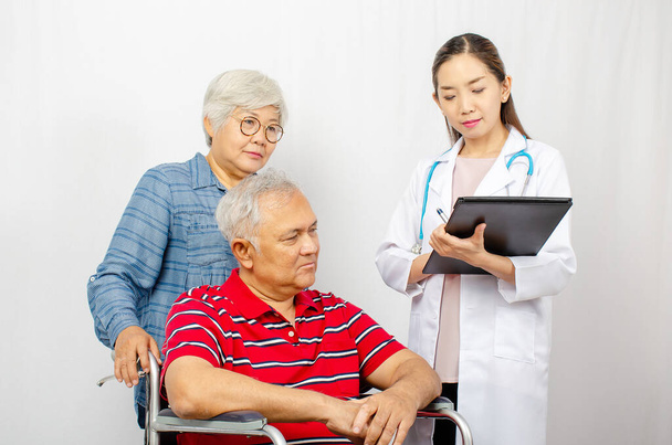 Donna asiatica Dottore che parla con coppia anziana in sedia a rotelle in ospedale. Bellissimo medico asiatico che si prende cura del paziente in sedia a rotelle, assistenza sanitaria e concetto medico - Foto, immagini