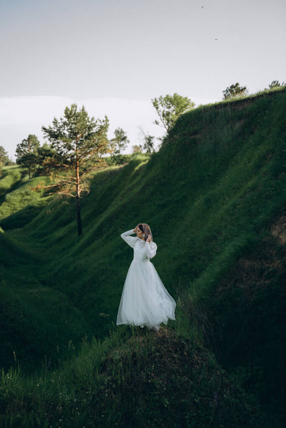fashionable woman in white dress standing  in the green mountain landscape - Φωτογραφία, εικόνα