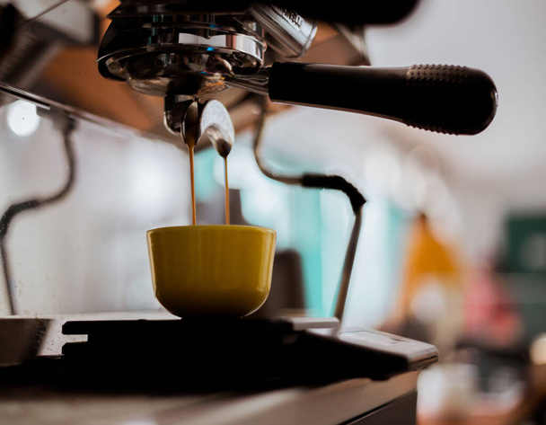 Espresso pouring from coffee machine into coffee cup. Soft focus - Photo, Image