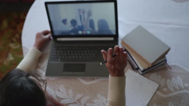 上の図では、現代の技術を使ってノートパソコンでオンライン教育中に老婦人がさらにコーチングを受けノートパソコンで手を挙げて答えを書きます - 映像、動画