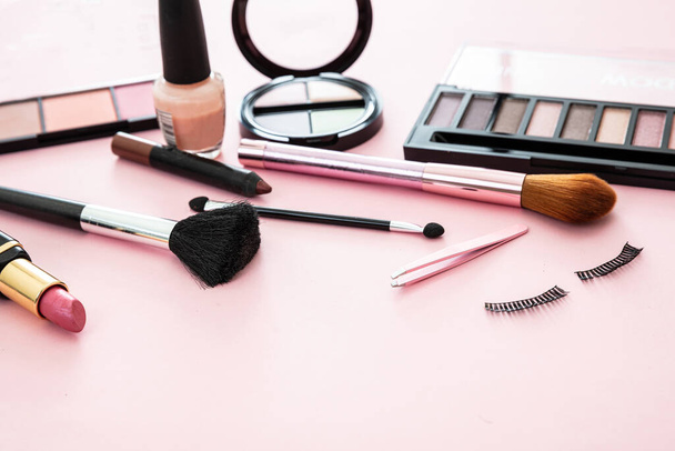 Make up cosmetics products. Lipstick and nail polish, eye shadows and blush, brushes and pencils against pink color background, copy space. - Photo, Image