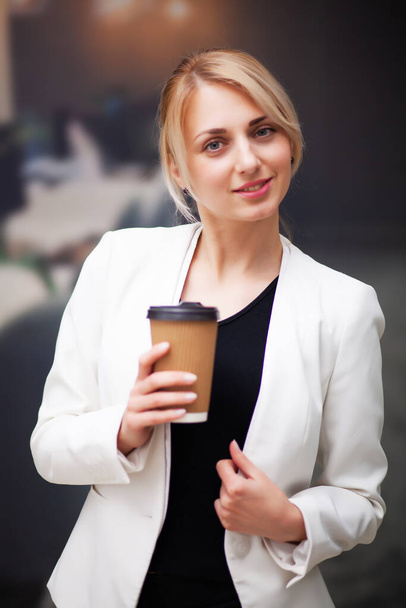 Business woman manager drinking coffee from a paper cup in the companys office - Fotoğraf, Görsel