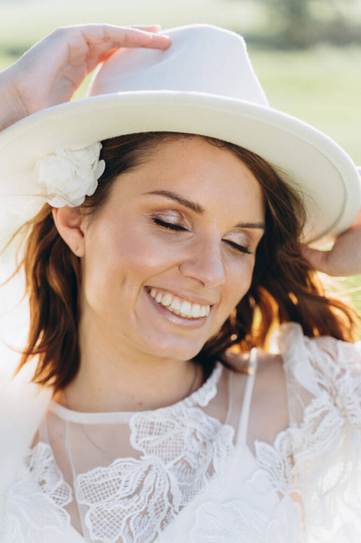 portrait of attractive woman wearing fedora hat posing in meadow - Fotó, kép