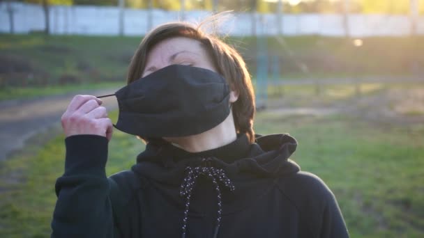 Kaukasische brünette Frau zieht Baumwollmaske aus, atmet tief durch und lächelt in die Kamera. Quarantäne-Endkonzept. Zeitlupenaufnahme - Filmmaterial, Video