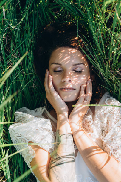 portrait of attractive woman wearing dress lying in the meadow  - Zdjęcie, obraz