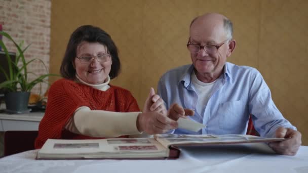 Familienerinnerungen, ein fröhliches Ehepaar, ein älterer Mann und eine Frau genießen Erinnerungen, die in einem alten Familienalbum mit Fotos blättern - Filmmaterial, Video