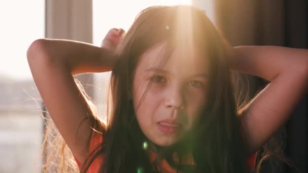 Portret brunetki na tle zachodzącego słońca. Piękne dziecko patrzące w kamerę, śmiejące się i robiące miny - Materiał filmowy, wideo