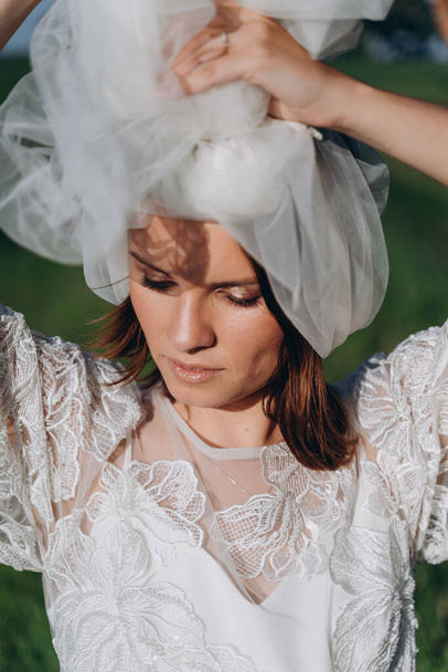 portrait of woman wearing veil and long white dress standing   in the field  - Photo, Image