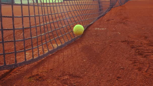 Rotolamento palla da tennis su un campo da tennis in terra battuta e sosta in rete, 4k, rallentatore 75fps - Filmati, video