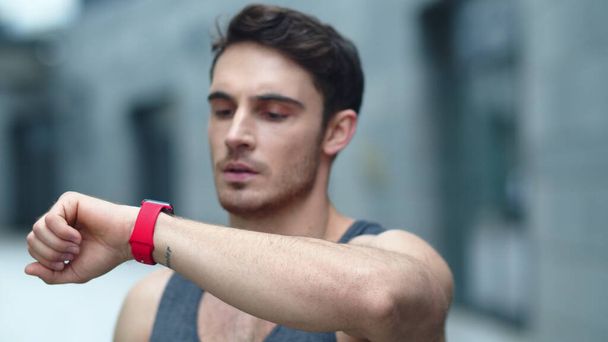 Closeup male athlete using smart clock outside. Fit man setting smart watch - Photo, Image