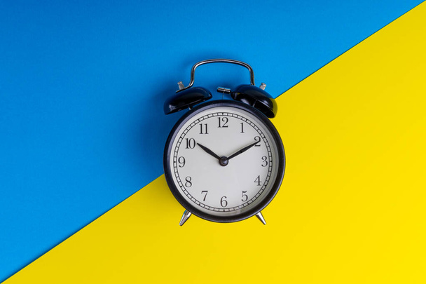 青と黄色の背景に目覚まし時計。事業概念 - 写真・画像