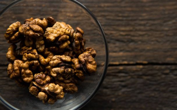 Walnut in a small plate on a vintage wooden table. Walnuts is a healthy vegetarian protein nutritious food. Natural nuts snacks. - Photo, image