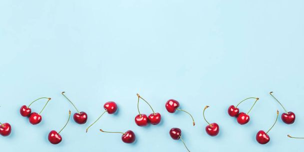 Bright pattern of ripe cherries on a blue background. - Zdjęcie, obraz