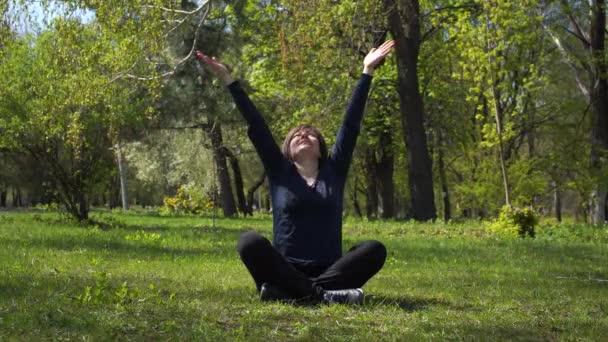 donna caucasica adulta che fa esercizi mattutini all'aperto, meditazione yoga in posa loto nel parco - Filmati, video