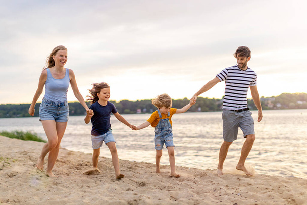 Foto de una familia de cuatro personas pasando el día en la playa
 - Foto, Imagen