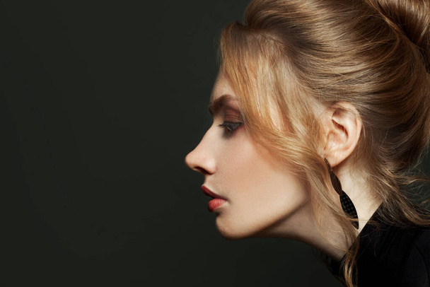 Elegantes weibliches Profil. Junge blonde Frau auf schwarzem Hintergrund, schönes Gesicht aus nächster Nähe - Foto, Bild