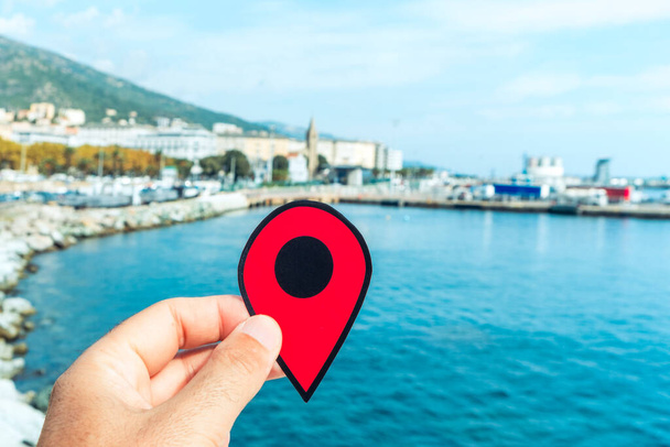 la main d'un jeune caucasien avec un marqueur rouge pointant le port de Bastia, en Corse, en France, avec le port commercial à droite et l'église Notre-Dame de Lourdes en arrière-plan - Photo, image