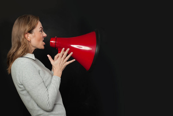 Mujer enojada gritando con megáfono de altavoz sobre fondo negro
 - Foto, imagen