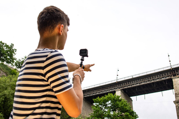 Teen junge herstellung video mit klein aktion kamera draußen - Foto, Bild
