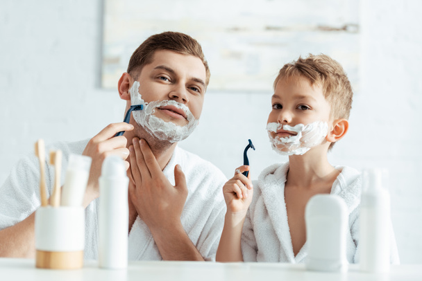 selective focus of father and son shaving in bathroom together - Photo, Image