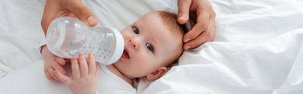 visão cortada de pai alimentando adorável bebê menino de mamadeira, imagem horizontal
 - Foto, Imagem