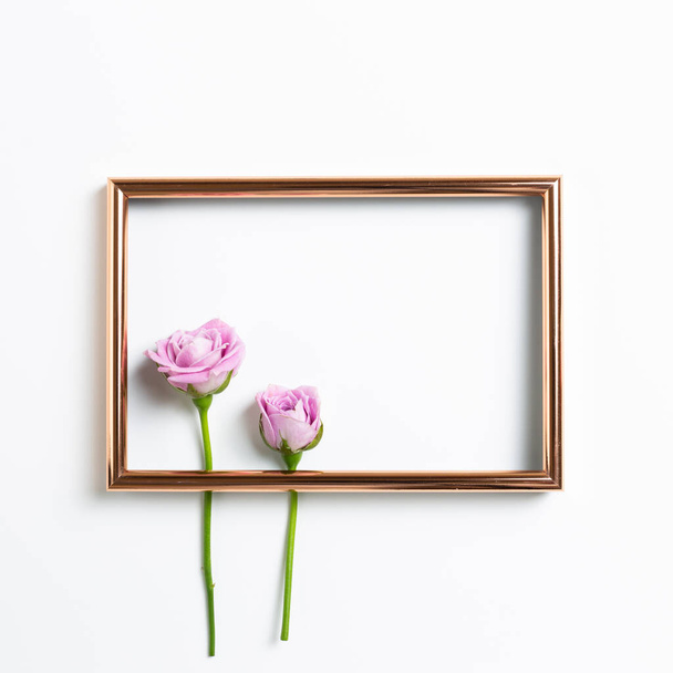 Leerer Fotorahmen mit rosa Rosenblüten auf weißem Hintergrund. Florale Komposition, flache Lage, Draufsicht, Kopierraum - Foto, Bild