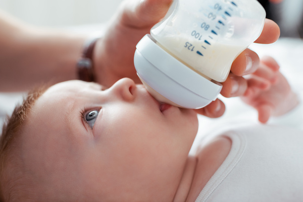 przycięty widok człowieka karmienie urocze niemowlę z butelki mleka - Zdjęcie, obraz