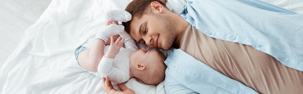 top view of happy father lying on bed face to face with cute baby boy, panoramic shot - Photo, Image