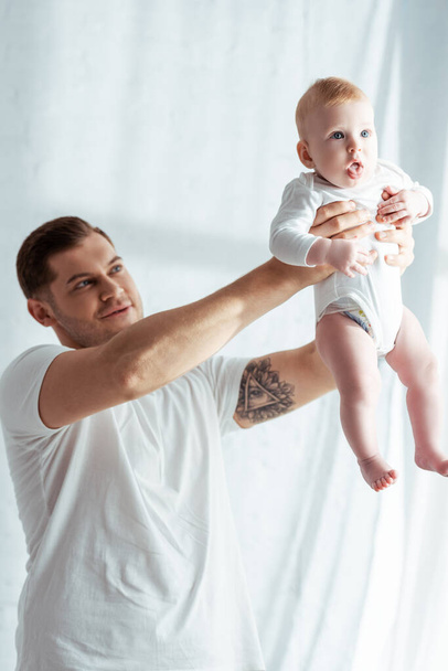 happy father holding adorable baby boy in outstretched hands - Фото, зображення