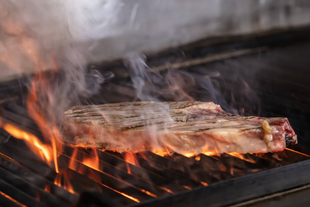 Rindersteaks auf dem Grill mit Flammen. Steaks auf flammendem Grill grillen und zielgerichtet schießen. - Foto, Bild