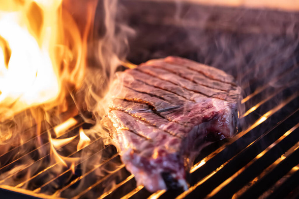 Beef steaks on the grill with flames. Grilling steaks on flaming grill and shot with selective focus. - Photo, Image