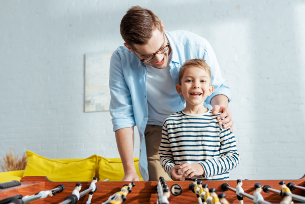 happy boy looking at camera while playing table soccer with father - Fotografie, Obrázek