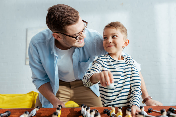 happy father and son looking at each other while playing table football  - Foto, Bild