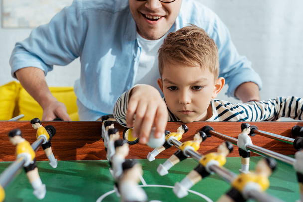 επιλεκτική εστίαση του πατέρα και του γιου που παίζουν επιτραπέζιο ποδόσφαιρο στο σπίτι - Φωτογραφία, εικόνα