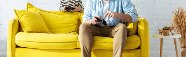 KYIV, UKRAINE - JUNE 9, 2020: cropped view of father and son playing video game with joysticks, horizontal image - Foto, Imagem
