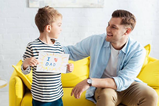 pai feliz olhando para o filho segurando pais dia cartão de saudação com letras e símbolo do coração
 - Foto, Imagem